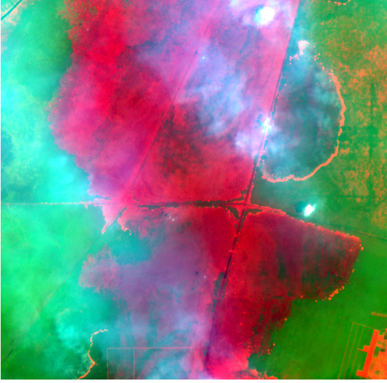 The same scene in shortwave infrared: the burn scar in dark red-brown, healthy forest in green and the fire front in bright orange.